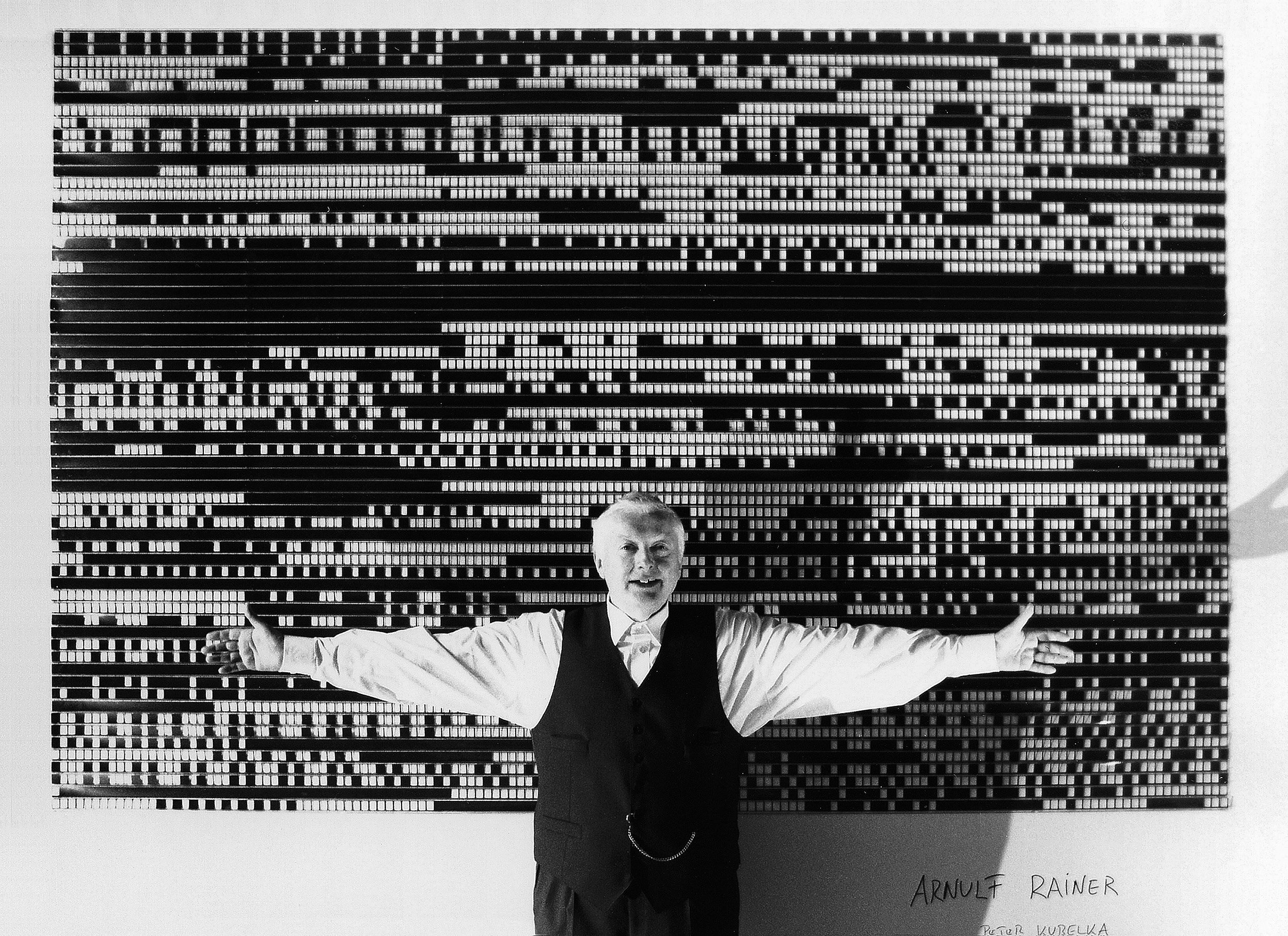 Peter Kubelka standing before the film strips of Arnulf Rainer